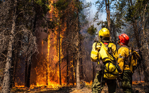 Fire brigade members fight the fires. great flames of fire surround them.