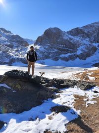 Rear view of woman standing on snowcapped mountain against sky