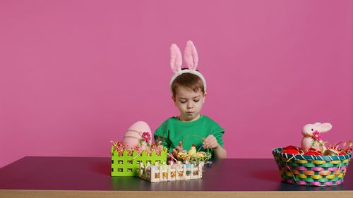 Portrait of boy playing with toys against yellow background