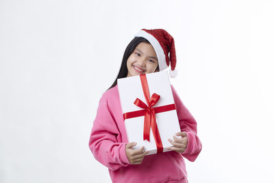 Portrait of smiling young woman wearing hat against white background