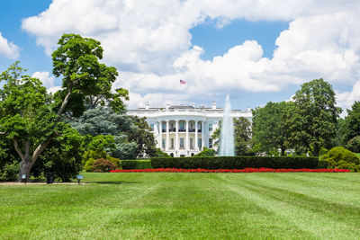 Trees in park against white house