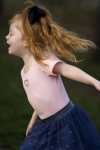 Side view of girl dancing on field