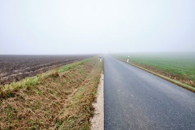 Road amidst field against clear sky