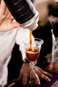 Midsection of man pouring drink on table