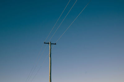 Low angle view of telephone line against clear blue sky