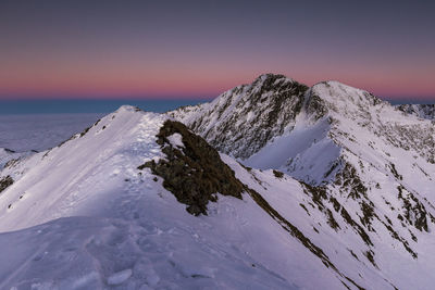 Scenic view of snowcapped mountains against clear sky during sunset