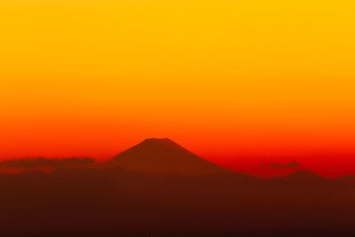 Scenic view of silhouette mountains against orange sky