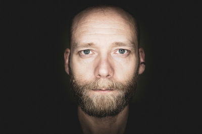 Portrait of young man against black background