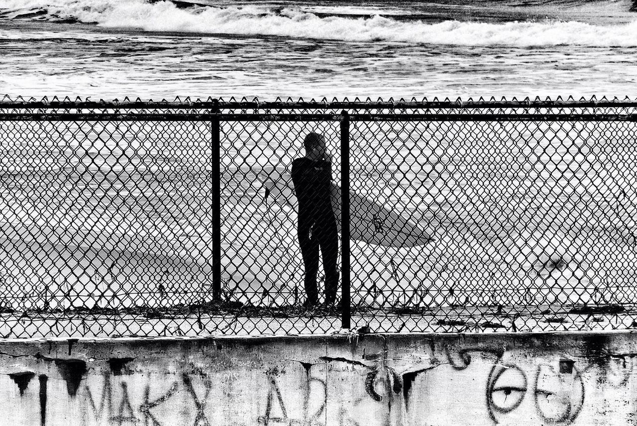 standing, silhouette, wall - building feature, full length, fence, lifestyles, walking, built structure, railing, protection, shadow, men, architecture, safety, wall, outdoors, day, security