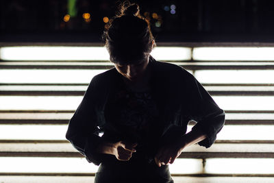 Silhouette rear view of woman looking through window and posing vogue fashion