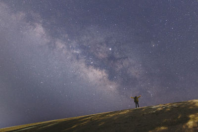 Silhouette man standing on field against star field in sky at night