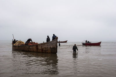 People on boat in sea against sky