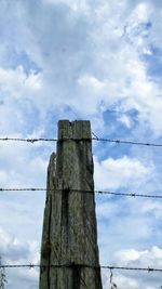 Low angle view of power lines against cloudy sky