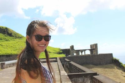 Portrait of smiling young woman in sunglasses against sky