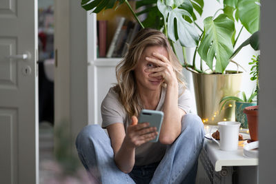 Shy woman using mobile phone at home