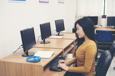 Side view of businesswoman using computer at desk in office