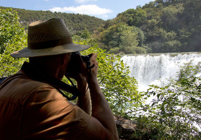 Side view of man photographing through binoculars