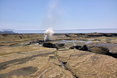 Water flowing through rocks on land against sky