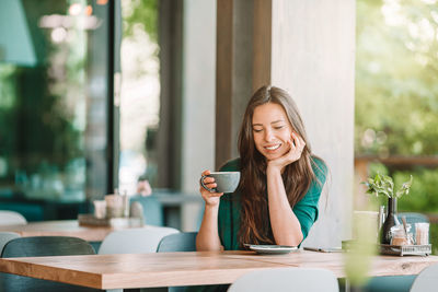 Smiling young woman using smart phone in restaurant