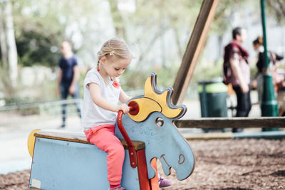 Cute girl sitting on rocking horse at playground