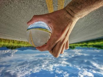 Upside down image of man holding crystal ball against road