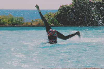 Low section of woman in bikini diving into infinity pool