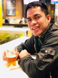 Portrait of smiling man with drink sitting on table