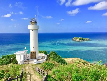 Lighthouse by sea against blue sky