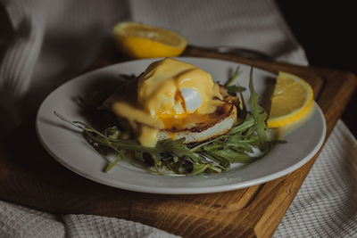 Eggs benedict and poached hollandaise sauce with arugula and lemon. delicious food for breakfast. 