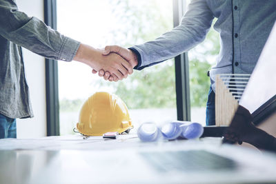 Midsection of engineer shaking hand with colleague