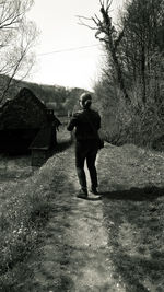 Rear view of man walking on field by building