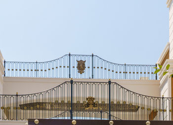 Low angle view of bird perching on railing against clear sky