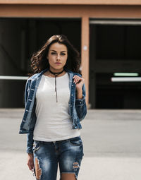 Portrait of beautiful young woman standing on footpath