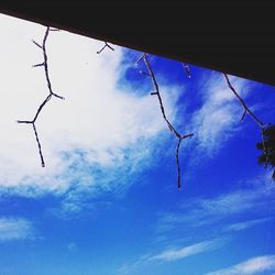 Low angle view of power lines against cloudy sky