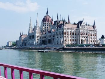 Danube river by hungarian parliament building against sky
