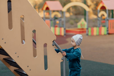 Little boy with down syndrome going to climb up on the stairs to slide himself