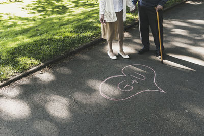 Senior couple drawed love heart with initials on tarmac