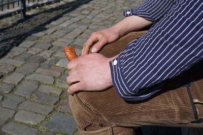 Close-up of man holding sausage on footpath