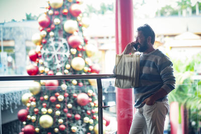 Rear view of man standing against illuminated christmas tree