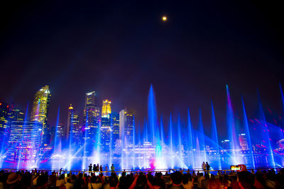 Crowd at illuminated city against sky at night