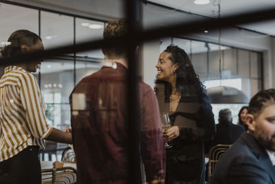 Smiling female and male colleagues talking in office during party