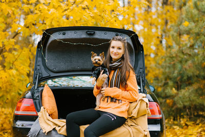 Happy girl and dog sitting in the trunk of a car in nature. friendship of a man and a dog, travel