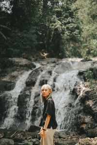 Full length of man standing on rock in forest