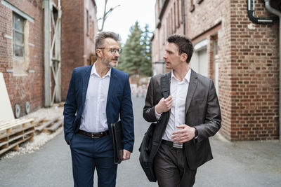 Two businessmen walking and talking at an old brick building