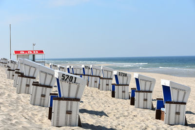 Hooded chairs on beach against clear sky