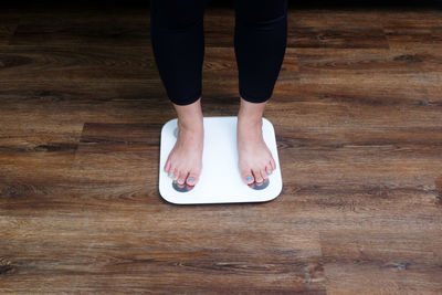 Low section of woman standing on wooden floor