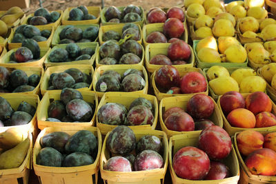 Plums and apples arranged in boxes at market for sale
