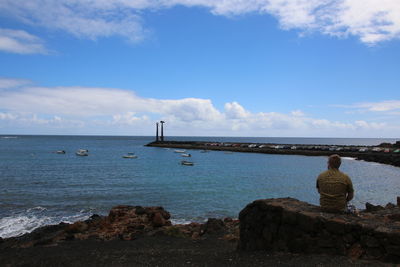 Rear view of people looking at sea against sky