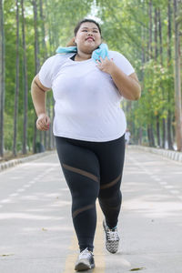 Full length of overweight woman running on road 