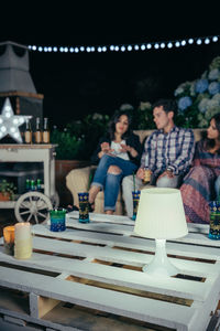 Friends sitting on sofa at patio during night